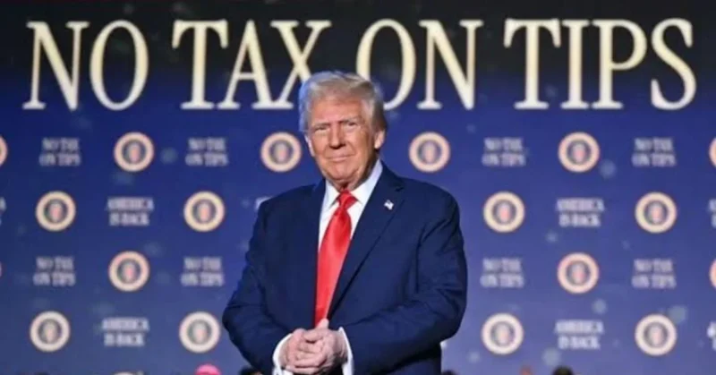 A man stands in front of a backdrop with the phrase "NO TAX ON TIPS" displayed prominently.