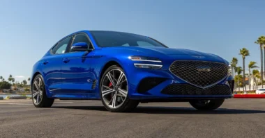 Blue 2025 Genesis G70 sport sedan parked on a sunny street.