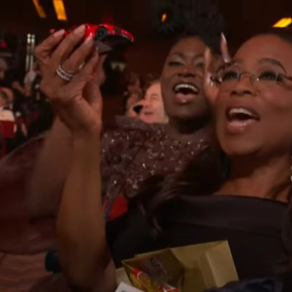 Oprah Winfrey smiling and holding a toy car during an award show.